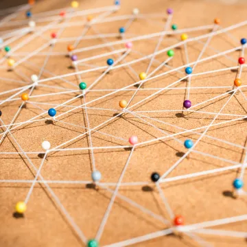 Ein Bild, auf dem bunte Stecknadeln zu sehen sind, zwischen denen Fäden gespannt sind