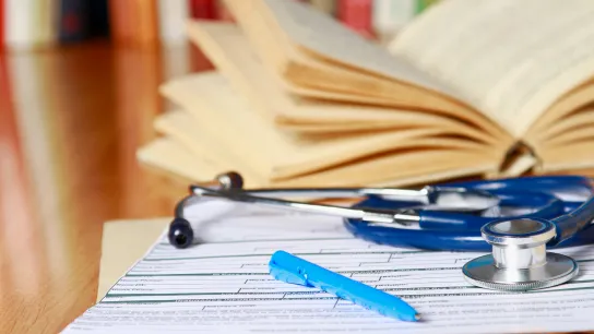 © shefkate - stock.adobe.com Ein Bild von einem Stethoskop, Büchern, Formularen und Stift