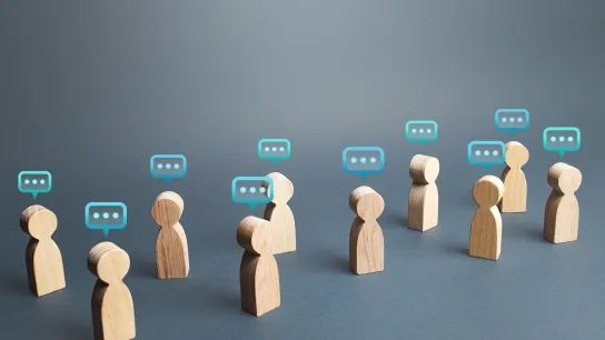 Zu sehen sind hölzerne Figuren, über deren Köpfen Sprechblasen mit drei Punkten darin schweben. 