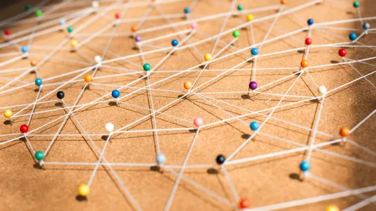 Ein Bild, auf dem bunte Stecknadeln zu sehen sind, zwischen denen Fäden gespannt sind